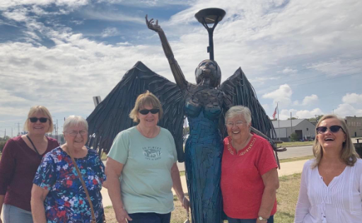 Five ladies posting next to a statue.